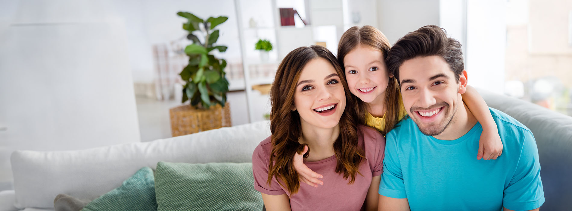 A family of four poses for a photo in their living room with a modern decor style.
