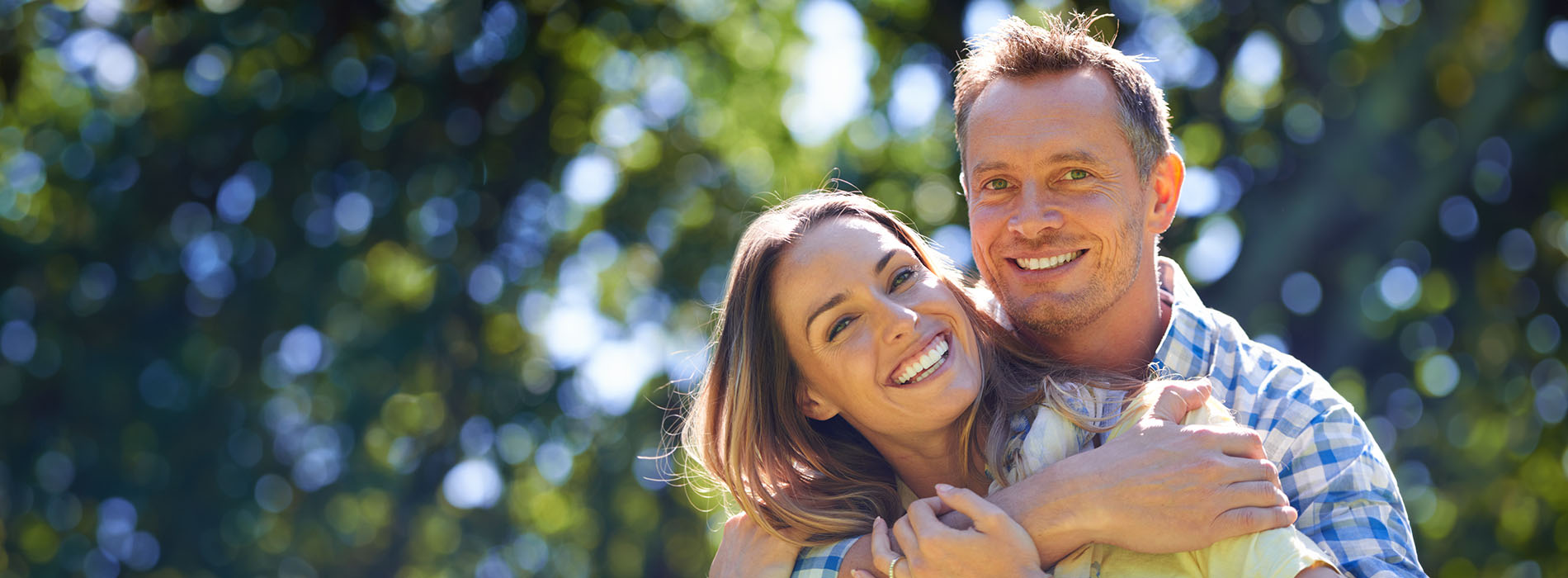 A man and woman are embracing each other outdoors during daylight with clear skies.